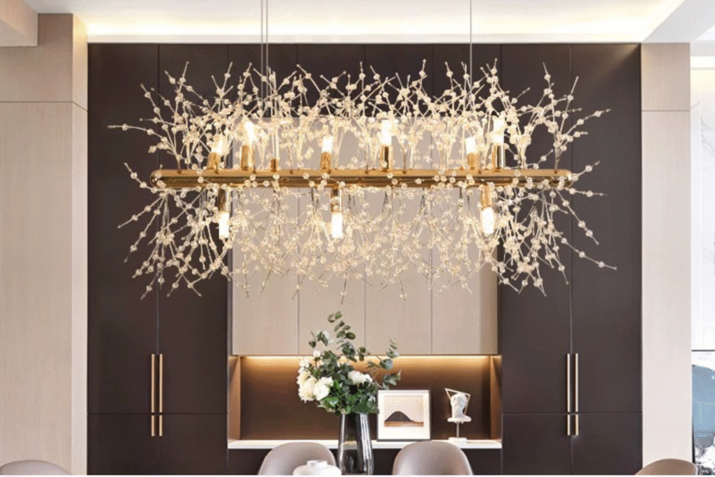 نجفة فاخرة بتصميم عصري وكريستالات راقية، تمنح المكان إضاءة مذهلة بلمسة ذهبية أنيقة.